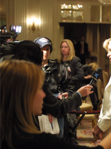 A woman talks to a group of reporters.