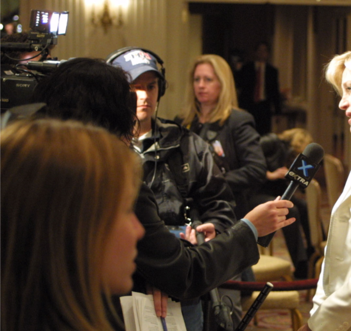 A woman talks to a group of reporters.