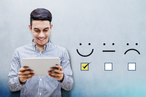 A man is smiling while looking at a piece of paper. Three happy, meh, unhappy icons are to his right; the happy one is checked.