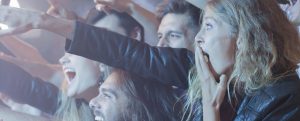 Young people are smiling and reaching toward the stage at a concert